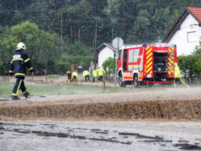 Red fire brigade engine,firefighting truck and firefighters rush to rescue when floods hit village in Europe after heavy rain, severe weather, rescue services